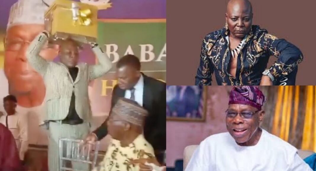 Charly Boy presenting a giant gift box to former President Olusegun Obasanjo during his 89th birthday celebration in Abeokuta.